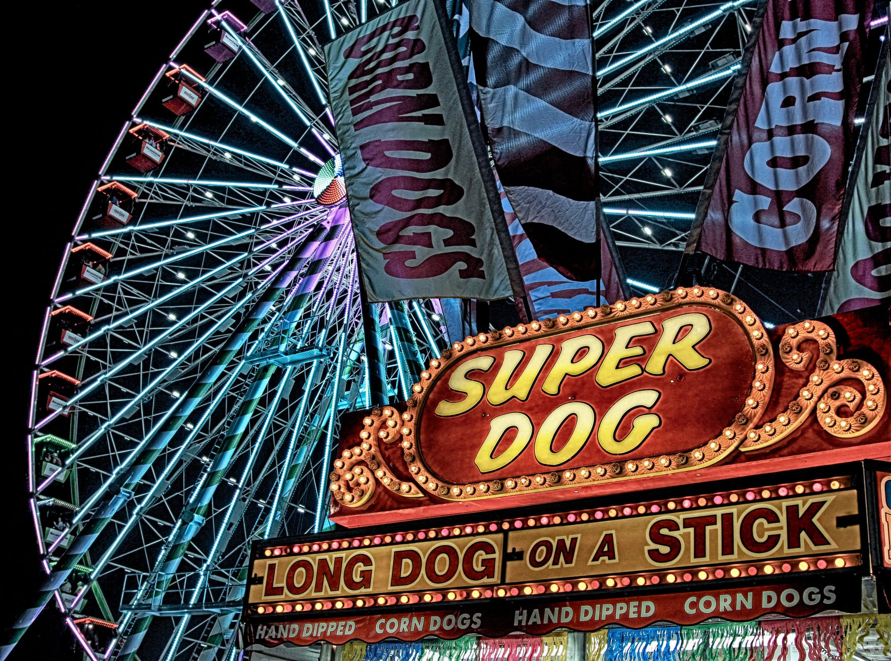 super dog hot dog food stall in front of ferris wheel during nighttime